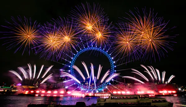 The London Eye lit up in blue with fireworks bursting in the night sky during New Year's Eve 2024 celebrations